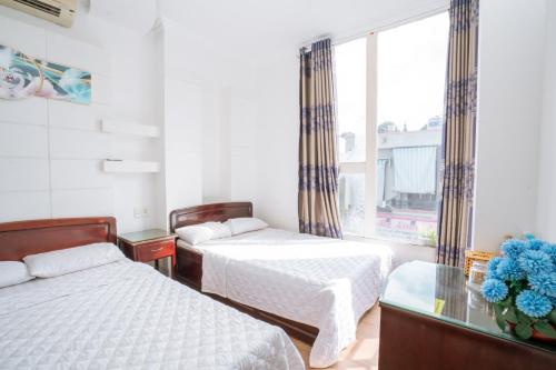邦美蜀Triệu Vũ Hotel & Apartment的一间卧室设有两张床和窗户。