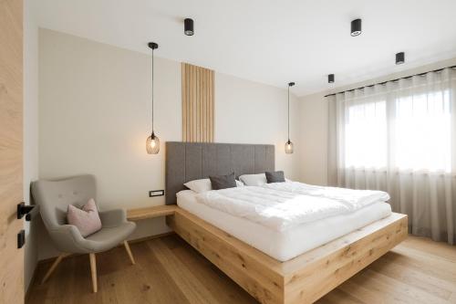 拉纳Boutique Hotel Wiesenhof - Adults Only的一间卧室配有一张大床和一把椅子