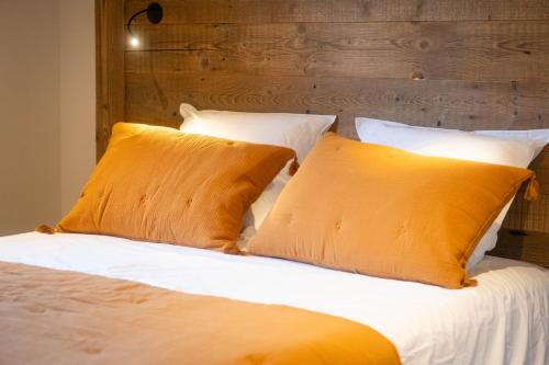 布里昂松Laltizoard的一张带两个橙色枕头的床和木制床头板