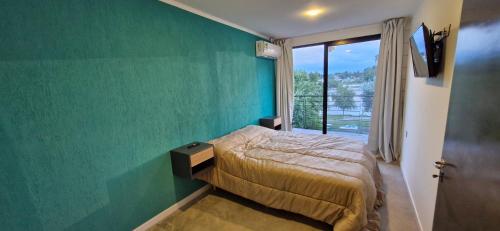 维拉卡洛斯帕兹Piso 3 frente al lago, centro Villa Carlos Paz pileta privada的一间卧室设有一张床和绿色的墙壁