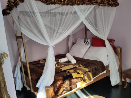 莫希Kilimanjaro Scenic Lodge的卧室配有带白色窗帘的天蓬床