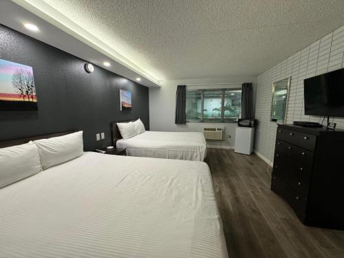温尼伯Travelodge by Wyndham Winnipeg的酒店客房设有两张床和一台平面电视。