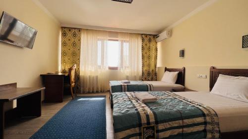 布哈拉AYUB Boutique Hotel的酒店客房设有两张床和窗户。