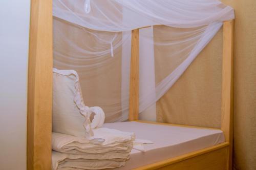 阿鲁沙Golden hour tiny house的一张带白色床单和天蓬的木制双层床