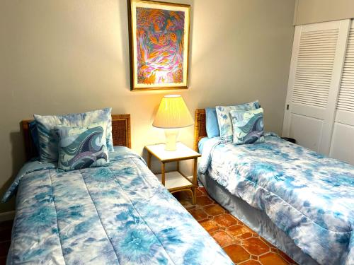乌马考Beach Villa 215的一间卧室配有两张床和一张带台灯的桌子