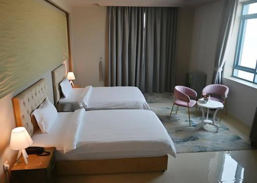 阿吉曼Bareen Hotel的酒店客房带两张床和一张桌子以及椅子。