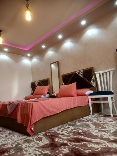 曼苏拉A 5-star hotel room in front of Mansoura University的一间卧室配有一张带红色床单的大床和椅子