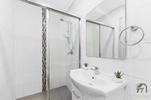 悉尼Entire Home in Lidcombe的白色的浴室设有水槽和淋浴。