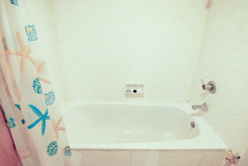 MakkasanWish Inn Ratchaprasong - Chidlom วิช อินน์ ราชประสงค์ ชิดลม的浴室配有白色的浴缸和淋浴帘