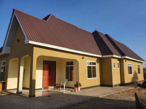 Boma la Ngombe4 BR/5 Bathroom Bungalow的一间有红色门和棕色屋顶的房子