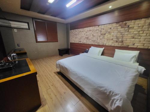 利川市Mokhwa Motel的卧室配有白色的床和砖墙