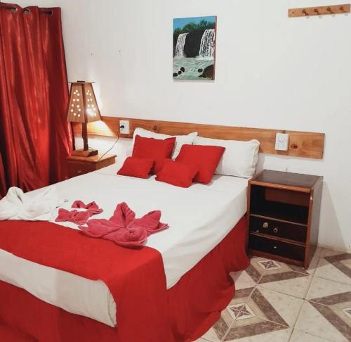 伊瓜苏港Hostel Damaris的一间卧室配有一张带红色枕头的大床