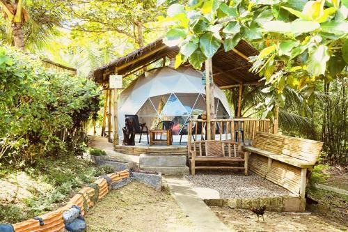 BalilihanEco Glamping Treehouses Closest Resort To All Tourist Attractions的一个带桌子和长凳的帐篷的房子