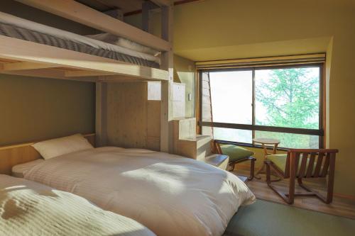 藏王温泉高宫树林酒店的一间卧室设有两张双层床、一张桌子和一个窗口。
