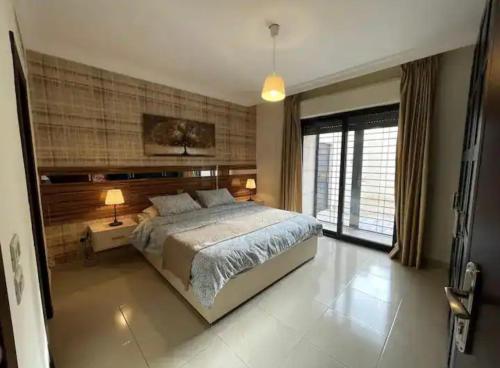 安曼Luxurious cozy apartment的一间卧室设有一张大床和一个大窗户