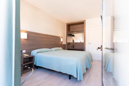 费雷列斯罗阿尔公寓酒店的一间卧室配有一张带蓝色毯子和一张桌子的床。