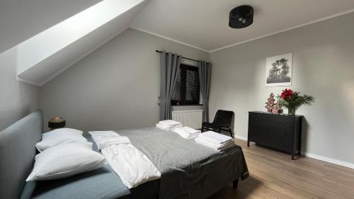 科瓦雷Apartamenty Czarna Perła的一间卧室配有一张带白色枕头和椅子的床
