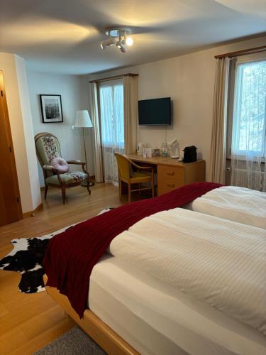 林根贝格Alpina Boutique Hotel Ringgenberg的酒店客房设有两张床、一张桌子和一台电视。
