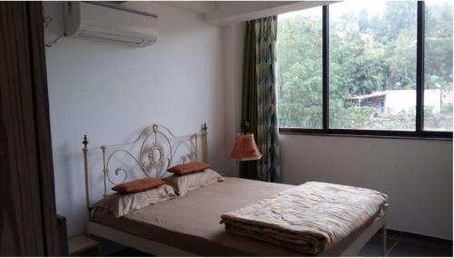 潘奇加尼Serinity Cliff的一间卧室设有一张床和一个大窗户