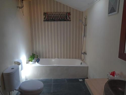 日惹Rosella Cottage - Homestay - Kitchen Yogyakarta的浴室配有白色浴缸和卫生间。