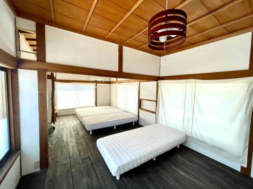 Murotsuギャラリー宿　INNAHOUSE ANDAGALLERY的客房设有两张床和天花板。