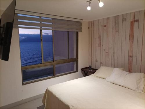 La ChimbaDepartamento Antofagasta. Playa privada的一间卧室设有一张床和一个大窗户