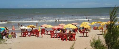 圣弗朗西斯科-迪伊塔巴波阿纳Pousada Casa da Praia SFI的一群人坐在海滩上的伞下