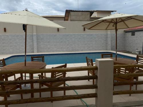 圣弗朗西斯科-迪伊塔巴波阿纳Pousada Casa da Praia SFI的两个桌子和遮阳伞坐在游泳池旁