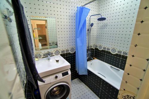 杜尚别Family 3-room apartment的一间带水槽和浴缸旁洗衣机的浴室