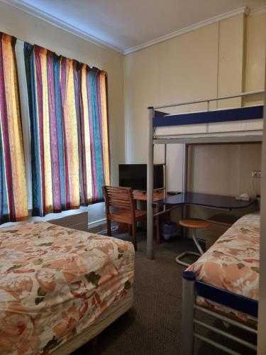怀希金十字酒店的酒店客房设有两张床、一张桌子和一张双层床。