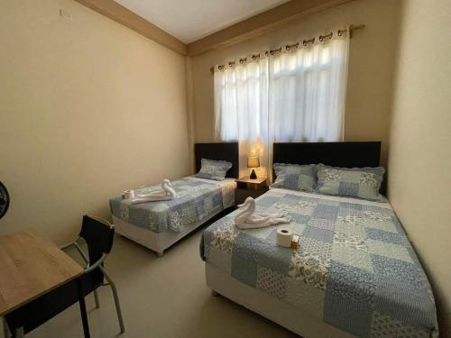 塔拉拉La Pequeña Suiza的一间卧室设有两张床、一张桌子和一个窗口