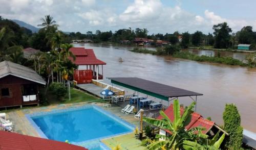 Ban DonsômPan guest house的河面上带房子和游泳池的图象