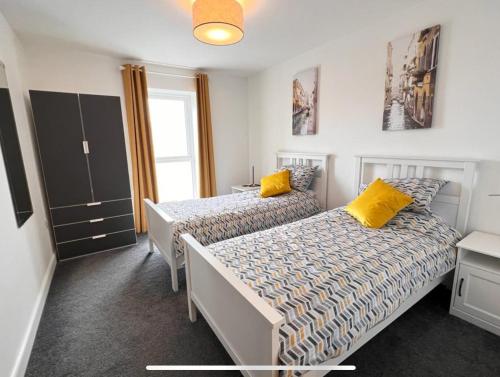 波特拉什Royal Atlantic View Apartment的一间卧室配有两张带黄色枕头的床