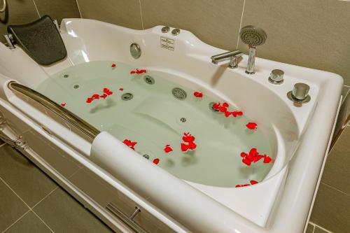 海防ZEN RIVERSIDE HOTEL & RESIDENCES的白色浴缸,里面装有红色的鲜花