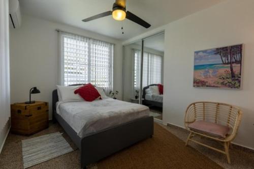 马纳蒂El Flamingo Beach Club的一间卧室配有一张床、风扇和椅子