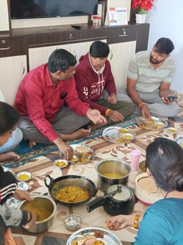 贾纳克布尔Mithila Culture Janakpurdham Homestay的一群坐在地板上吃食物的人