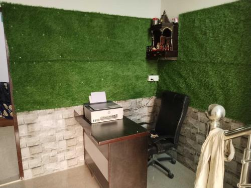 尼玛纳OYO Neelkanth Hotel & OYO Rooms的一个带绿色墙壁的办公室和一张带打印机的书桌