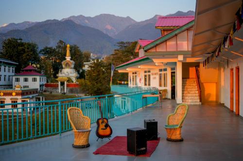 比尔瓦Chokling ArtHouse - The Treasure of Himalayas的阳台配有椅子和扬声器,享有山脉背景