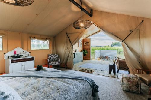 哈士汀Villas & Vines Glamping的帐篷内一间卧室,配有一张床和一间厨房