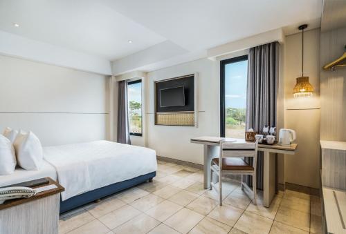普拉亚Swiss-Belcourt Lombok的配有一张床和一张书桌的酒店客房