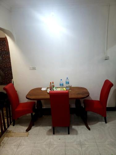 姆万扎Dwina Apartements的一张桌子、红色的椅子和两瓶水