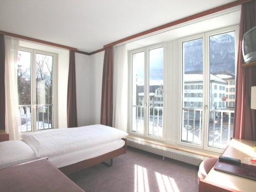 格拉鲁斯Hotel Post Glarnerhof的一间卧室设有一张床和大窗户