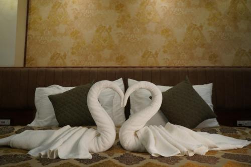 普鲁利耶Swet Palash Resort的两只毛巾天鹅在床上形成心