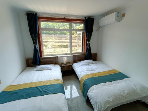 密云古北口长城聚仙居民宿的带窗户的客房内的两张床