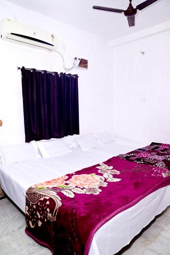 JasidihSHIVAY GUEST HOUSE的一间卧室配有一张床铺,床上铺有紫色毯子