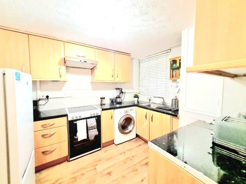 Havering atte BowerCosy Luxurious 3 Bedroom House, Free Parking, Free WiFi, Private Garden, Free Netflix的厨房配有木制橱柜、洗衣机和烘干机