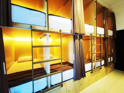 库塔Fora Capsule Hostel Tuban Kuta Bali的一间玻璃墙客房,里面设有一张床