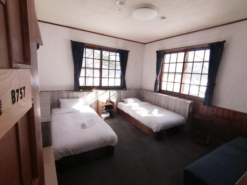 白马村Pilot Lodge的客房设有两张床、一张沙发和两个窗户。