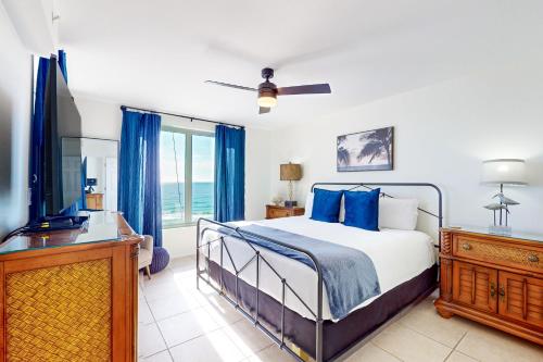 沃尔顿堡滩Island Princess 704的一间卧室配有一张带蓝色枕头的床和电视。