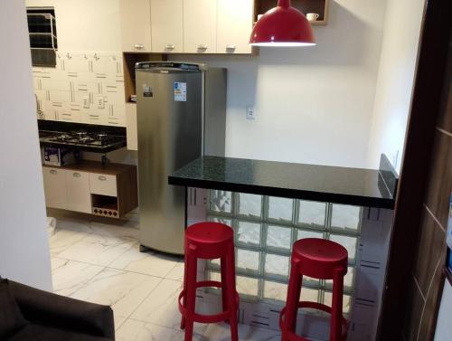 贝伦Apartamento novo e confortável的厨房配有柜台和2张红色凳子